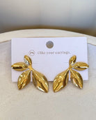 A pair of gold leaf-shaped stud earrings displayed on a white card that reads 'i like your earrings.' with a small 'pk' logo, set against a neutral cream background.